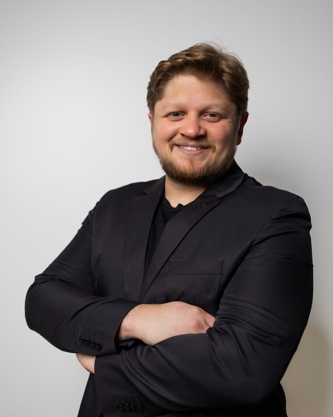 Dr. Yuri Vasques sorrindo, de blazer preto e braços cruzados