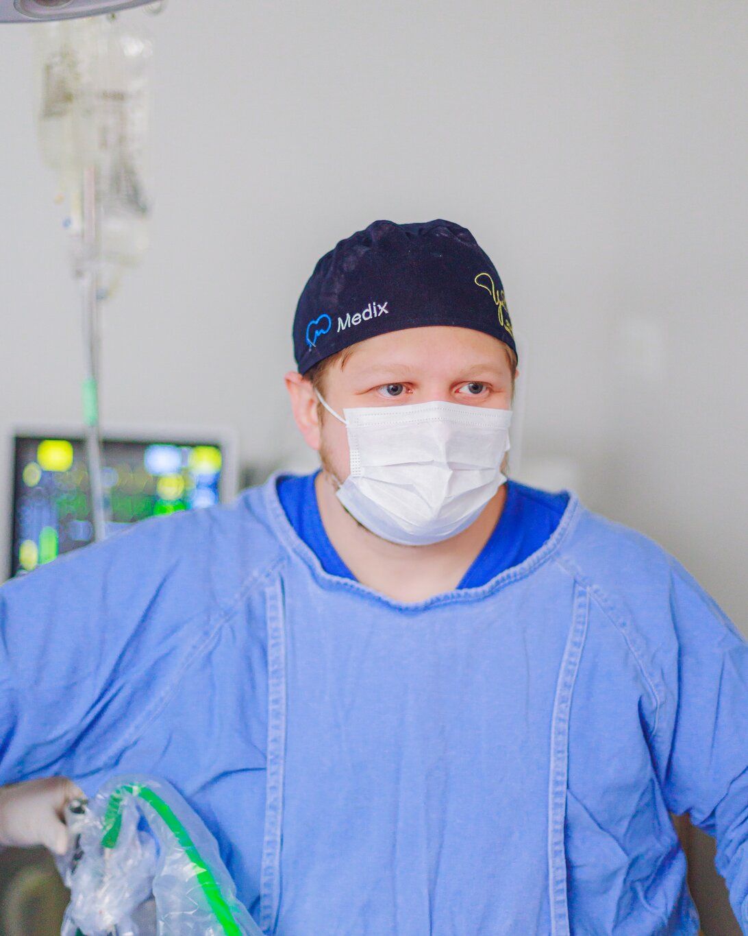 Dr. Yuri Vasques de máscara e touca, olhando para a câmera durante uma cirurgia