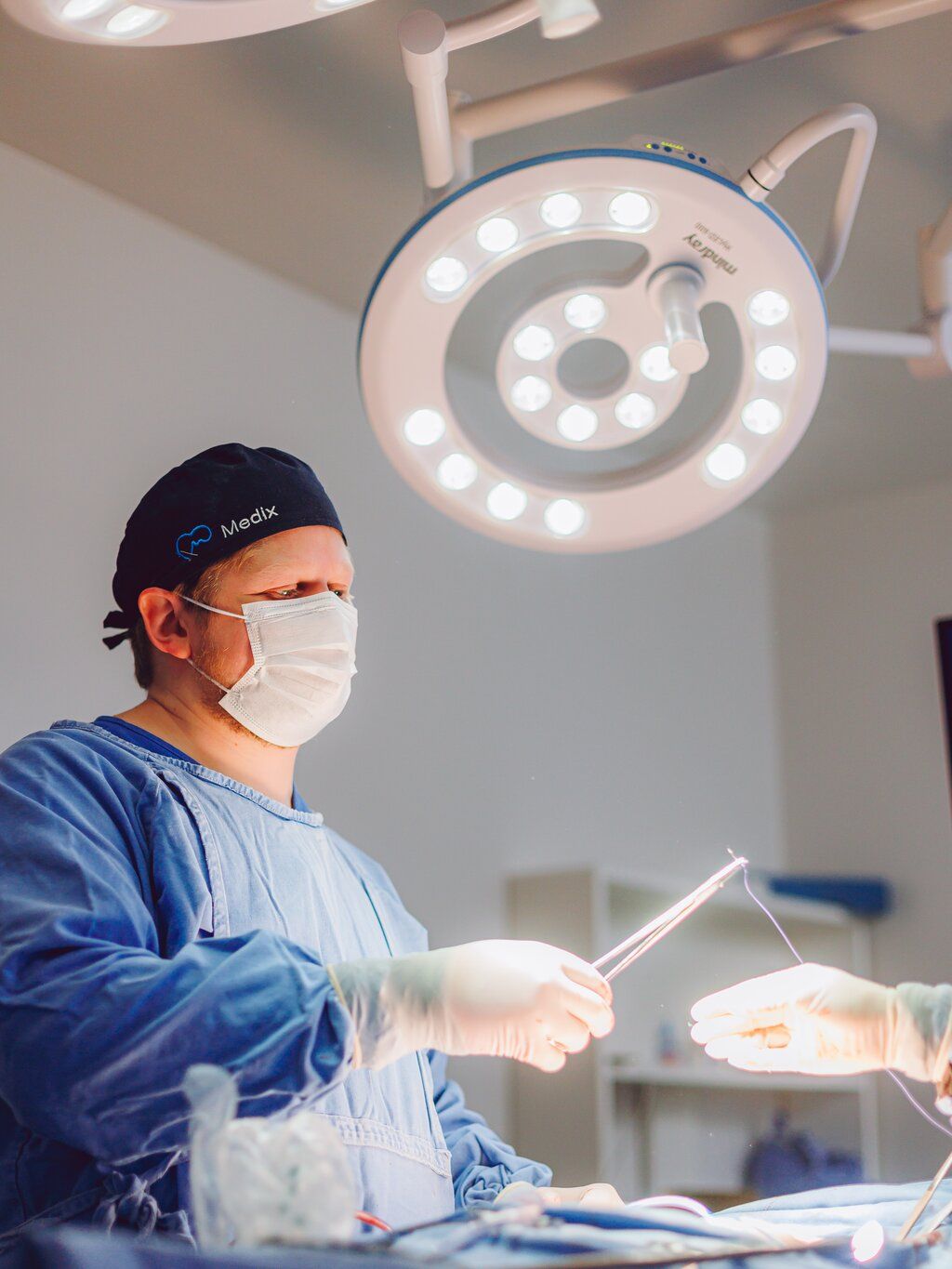 Dr. Yuri Vasques operando sob o foco de luz do centro cirúrgico